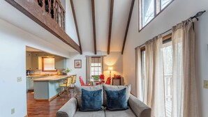 A cozy living room with a sofa, a dining area with chairs, and a kitchen in the background. - Rustic charm with modern amenities, ensuring a comfortable and memorable stay. (Mountain View)