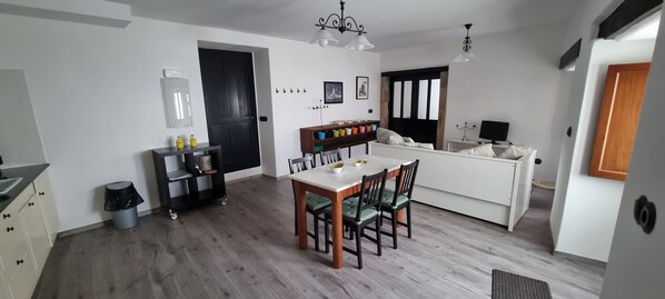 A modern kitchen with a dining area, wooden flooring, and a black door. - Lovely apartment in lCastropol with Patio (Castropol)