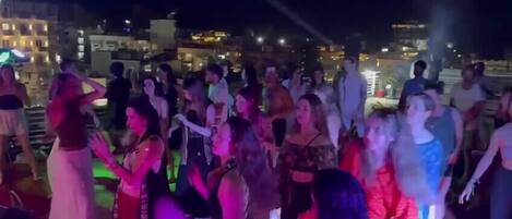 En fest på taget med mange mennesker, der danser og hygger sig.