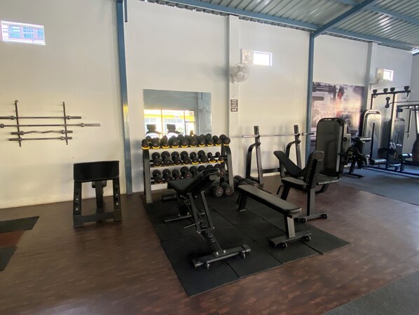 A gym with weightlifting equipment, benches, and dumbbells. - Bunk Hostel Rishikesh (Rishikesh)