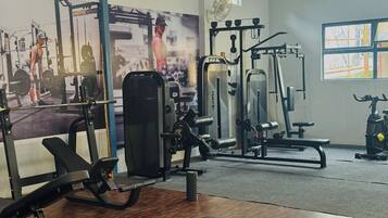 A gym with various exercise equipment, including a bench, weight machines, and a mirror.