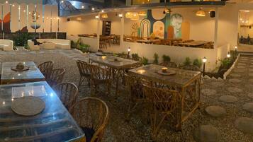 Un espace de restauration en plein air, avec des tables et des chaises, entouré de murs décoratifs et de plantes.