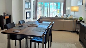 A spacious living room with a large dining table, a sofa, and a TV. - Charming 2-bedroom in a luxury enclosed condominium in Vila Sol with AC, WiFi (Quarteira)