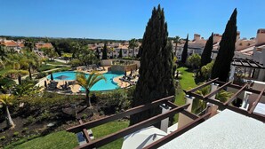 A resort with a central swimming pool, palm trees, and a view of other buildings. - Charming 2-bedroom in a luxury enclosed condominium in Vila Sol with AC, WiFi (Quarteira)