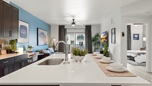 A modern kitchen with a central island, dark cabinets, and a view to the living area.