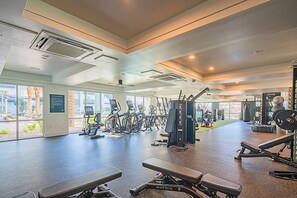 A spacious gym with various exercise equipment, large windows, and a view of the outdoors.