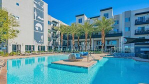 A modern hotel with a swimming pool, palm trees, and lounge chairs. - Kierland Area | Sun-Kissed Stay | Pool & Hot Tub (Phoenix)