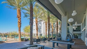 An outdoor lounge area with seating, a pool, and palm trees. - Kierland Area | Sun-Kissed Stay | Pool & Hot Tub (Phoenix)