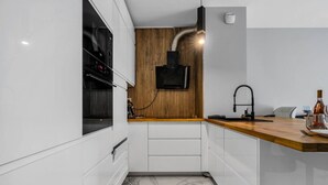 A compact kitchen with white cabinetry, a wooden countertop, a built-in oven, and a black faucet. - Białołęka Apt - 61m2, Parking & Balcony - by Rentujemy (Warszawa)