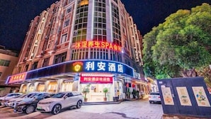 Ein Hotel mit geschwungener Fassade, mehreren Stockwerken und einem Spa im Erdgeschoss. Vor dem Gebäude sind mehrere Autos geparkt, und es ist nachts gut beleuchtet.