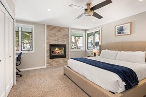 Relax in this serene bedroom with a large bed, fireplace, and brick accent wall.