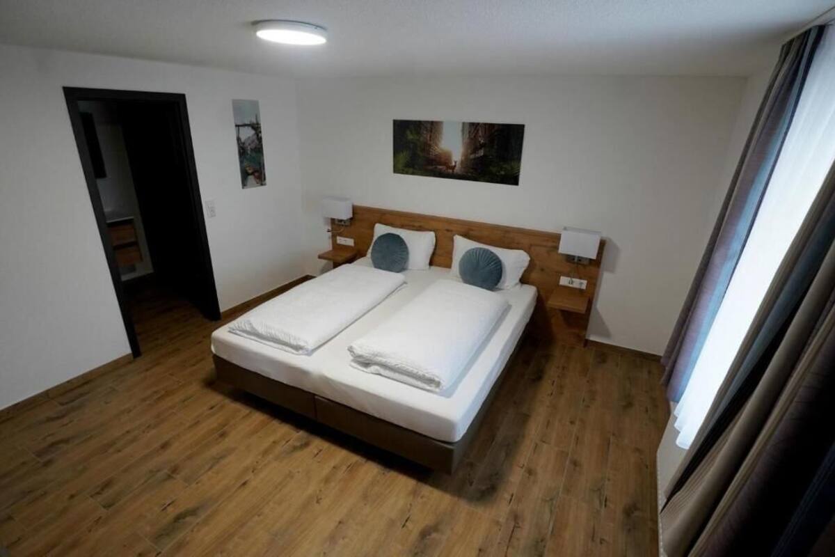 Un lit double avec deux oreillers, une tête de lit en bois et une table de chevet avec une lampe.