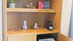 A compact kitchenette with a built-in refrigerator, a coffee maker, and a small potted plant. - Hotel 7 Winde (Spaichingen)
