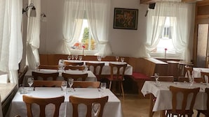 A restaurant with wooden tables and chairs, white tablecloths, and large windows with sheer curtains. - Hotel 7 Winde (Spaichingen)
