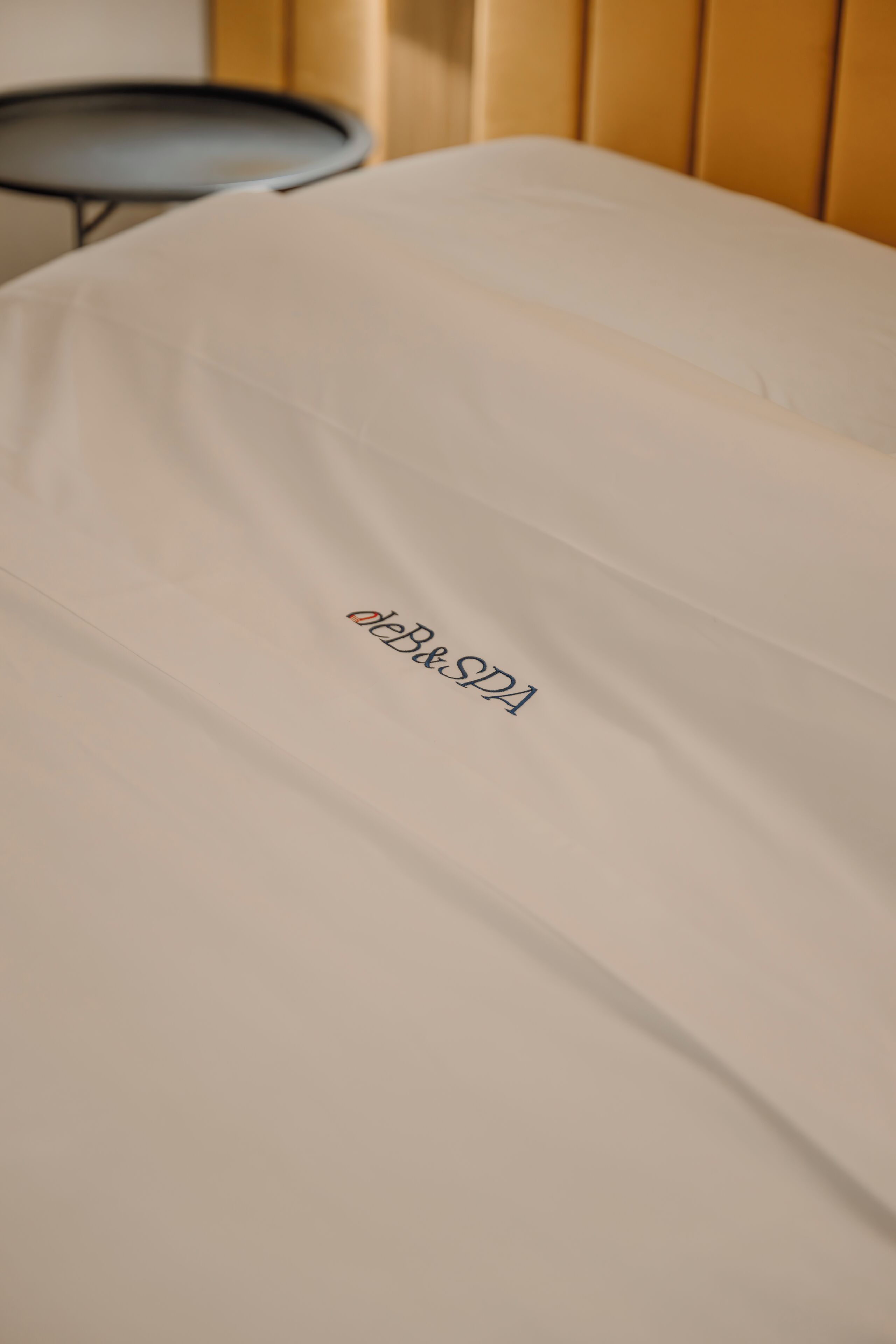 Un lit avec un drap blanc et un logo imprimé dessus.