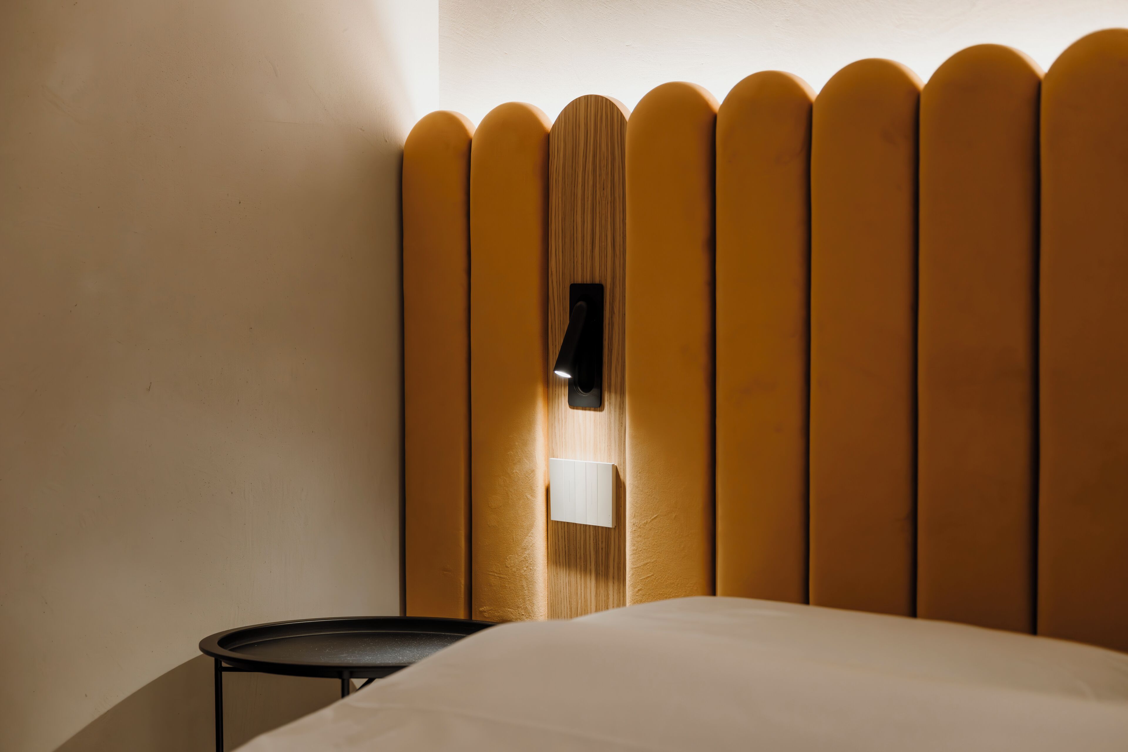 Ein Schlafzimmer mit einem Bett, einem kleinen runden Tisch und einer Wandleuchte.