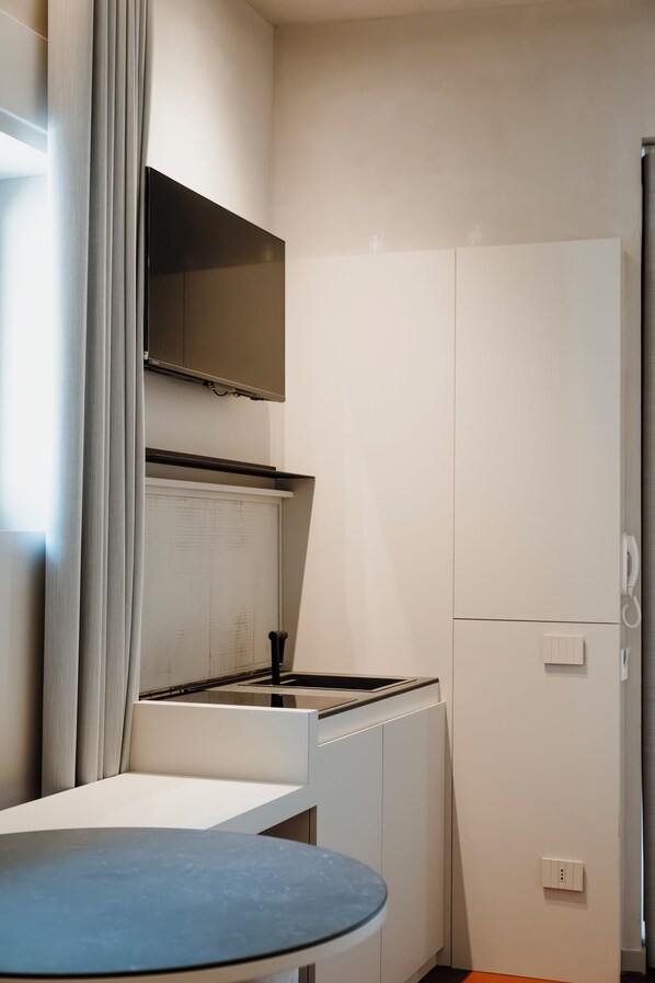 A compact kitchen with a stove, a small table, and a cabinet. - deB&SPA (Altamura)