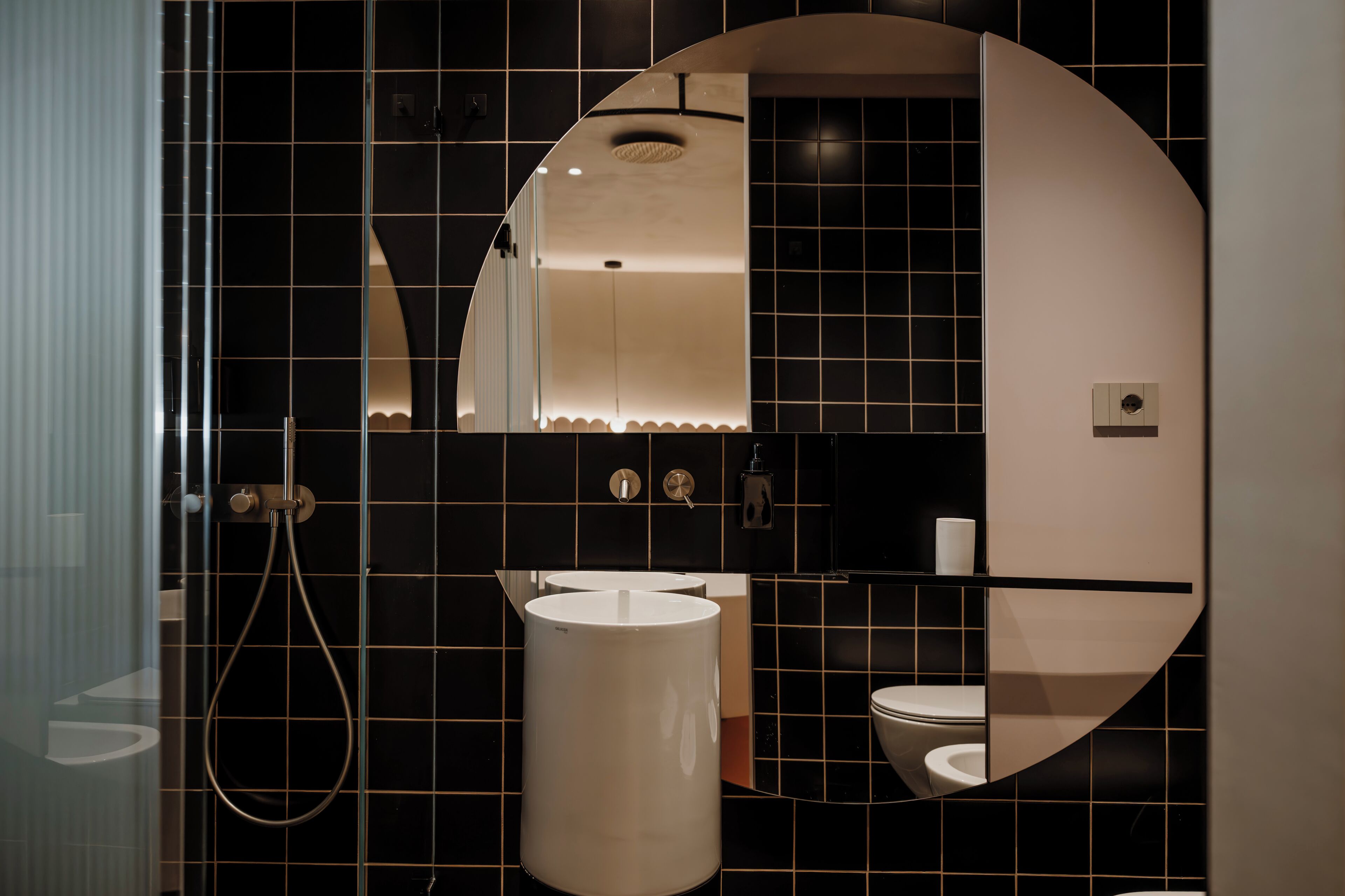 A modern bathroom with a large mirror, a sink, and a toilet.
