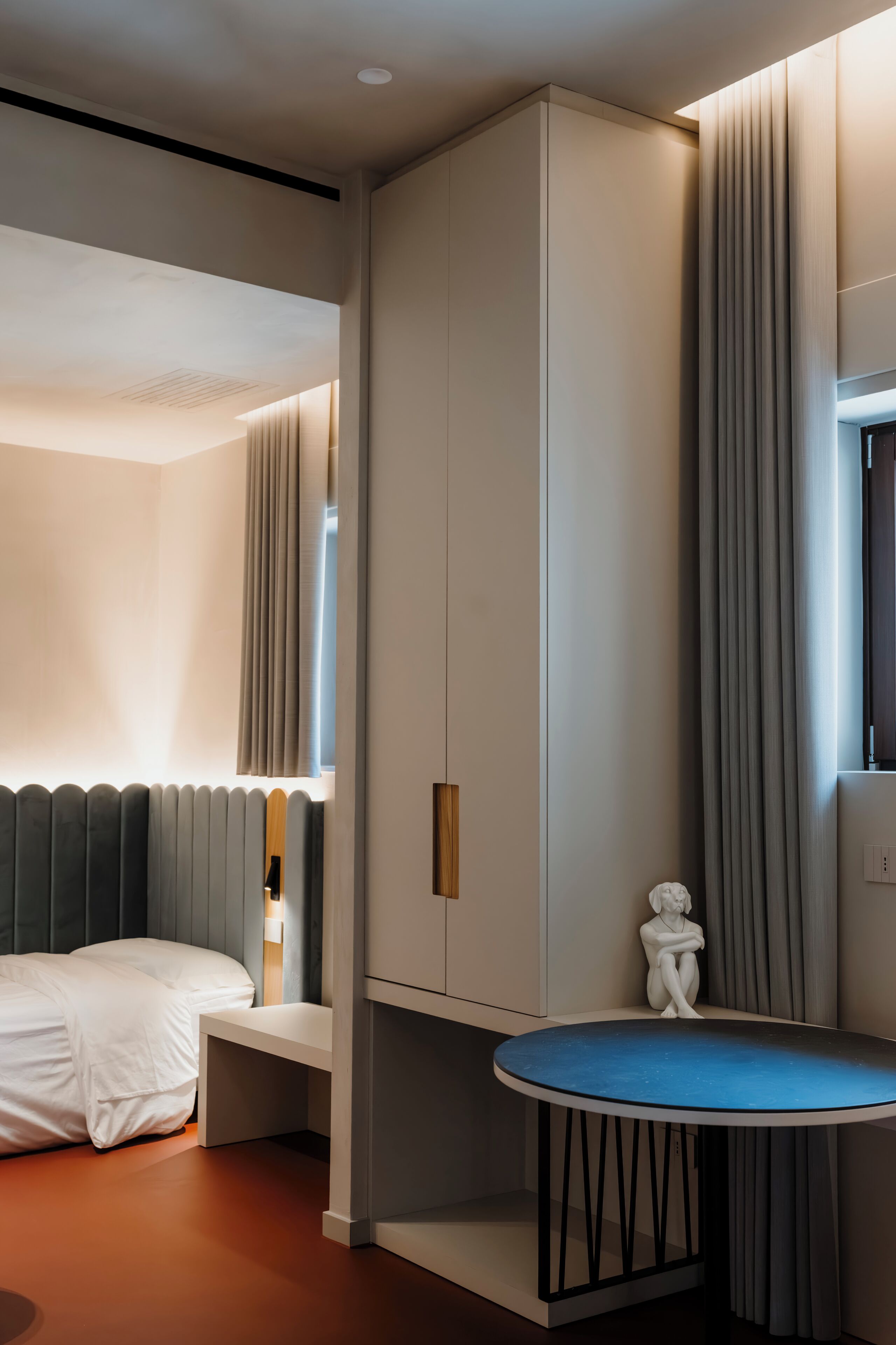 Une chambre d’hôtel moderne, équipée d’un lit, d’une petite table et d’une armoire.