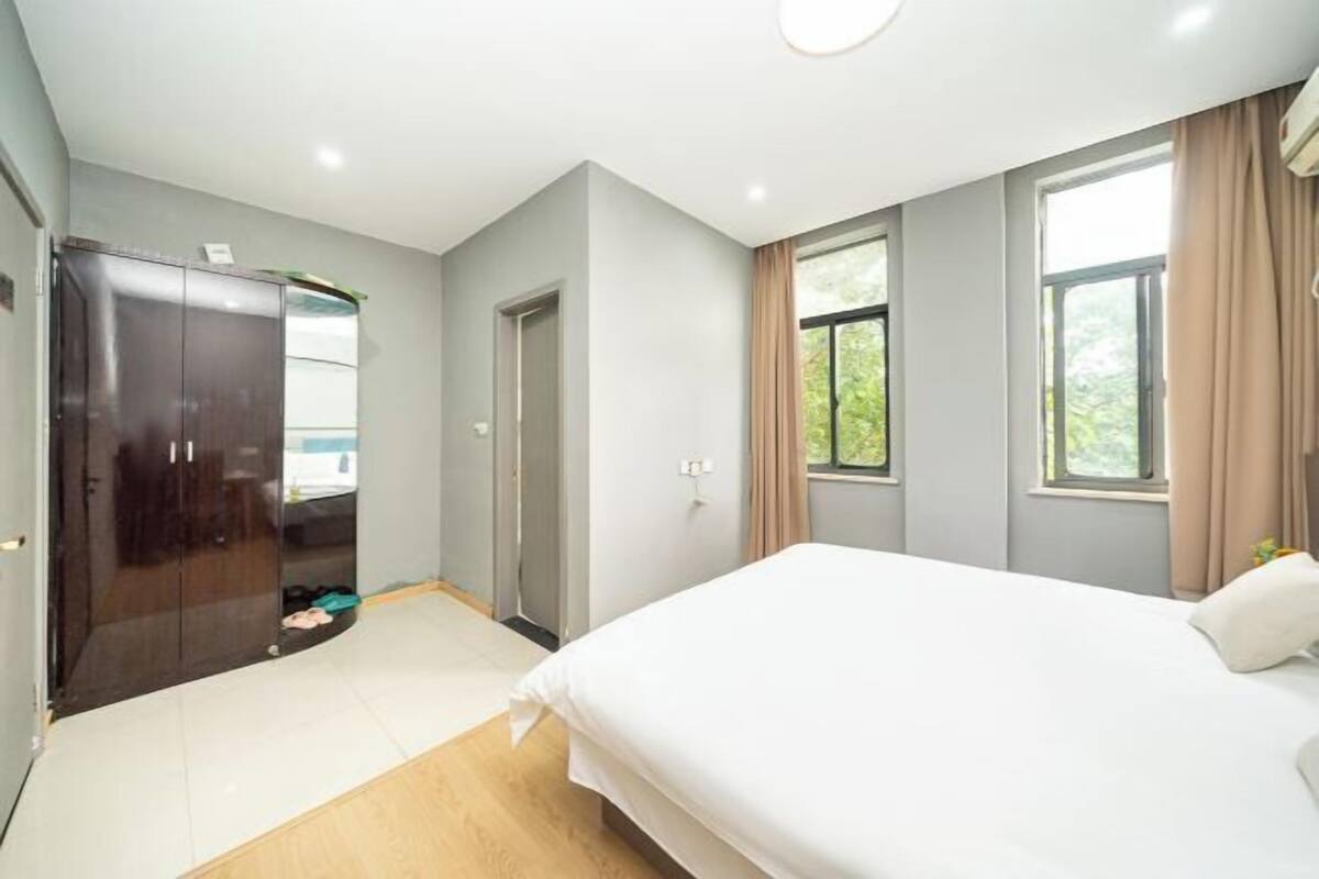 A bedroom with a bed, a wardrobe, a door, and windows.