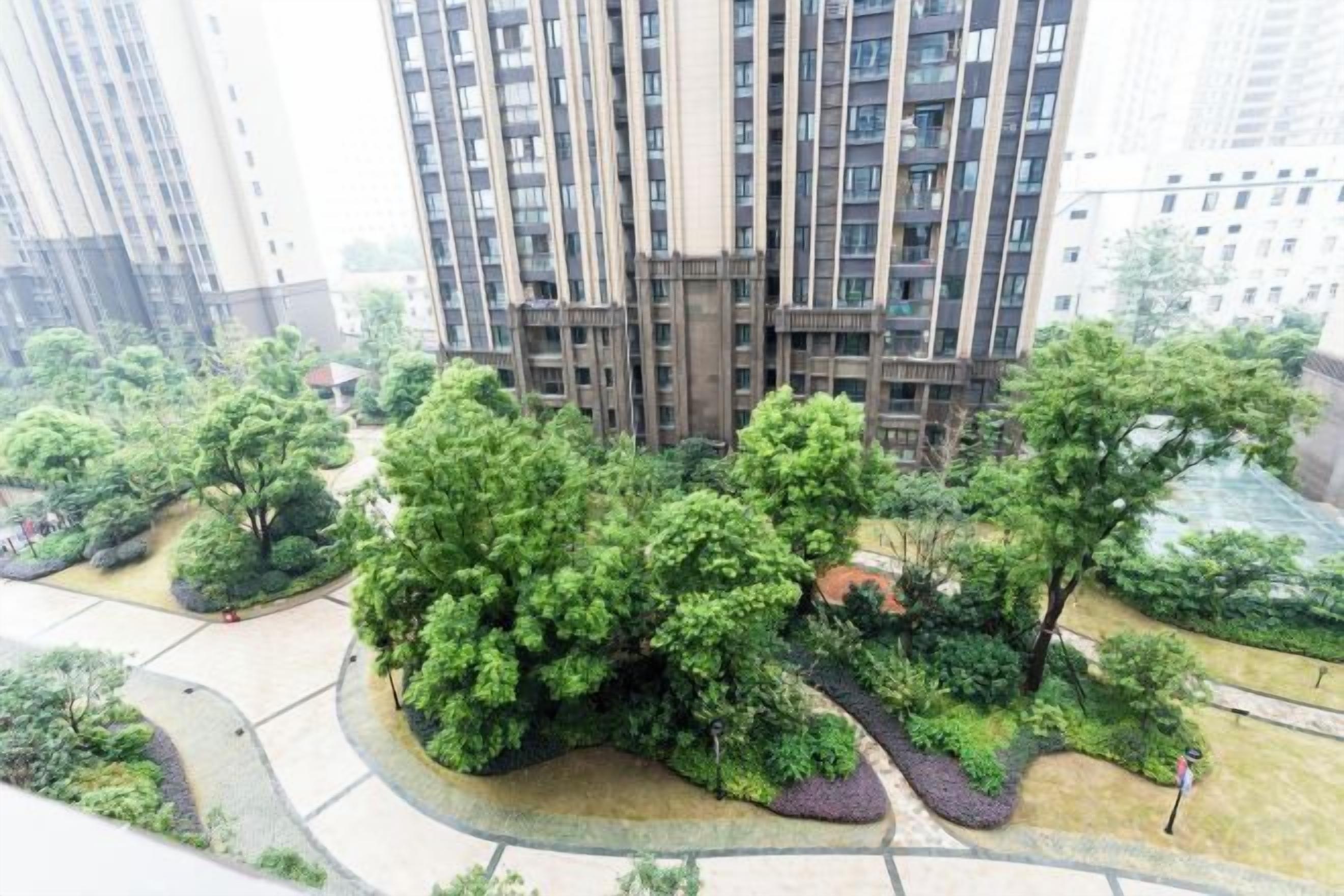 A high-rise building with a central courtyard surrounded by greenery.