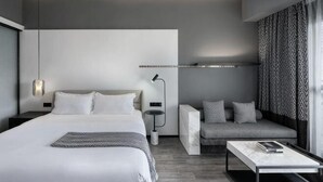 Een moderne hotelkamer met een groot bed, nachtkastje en een bank.