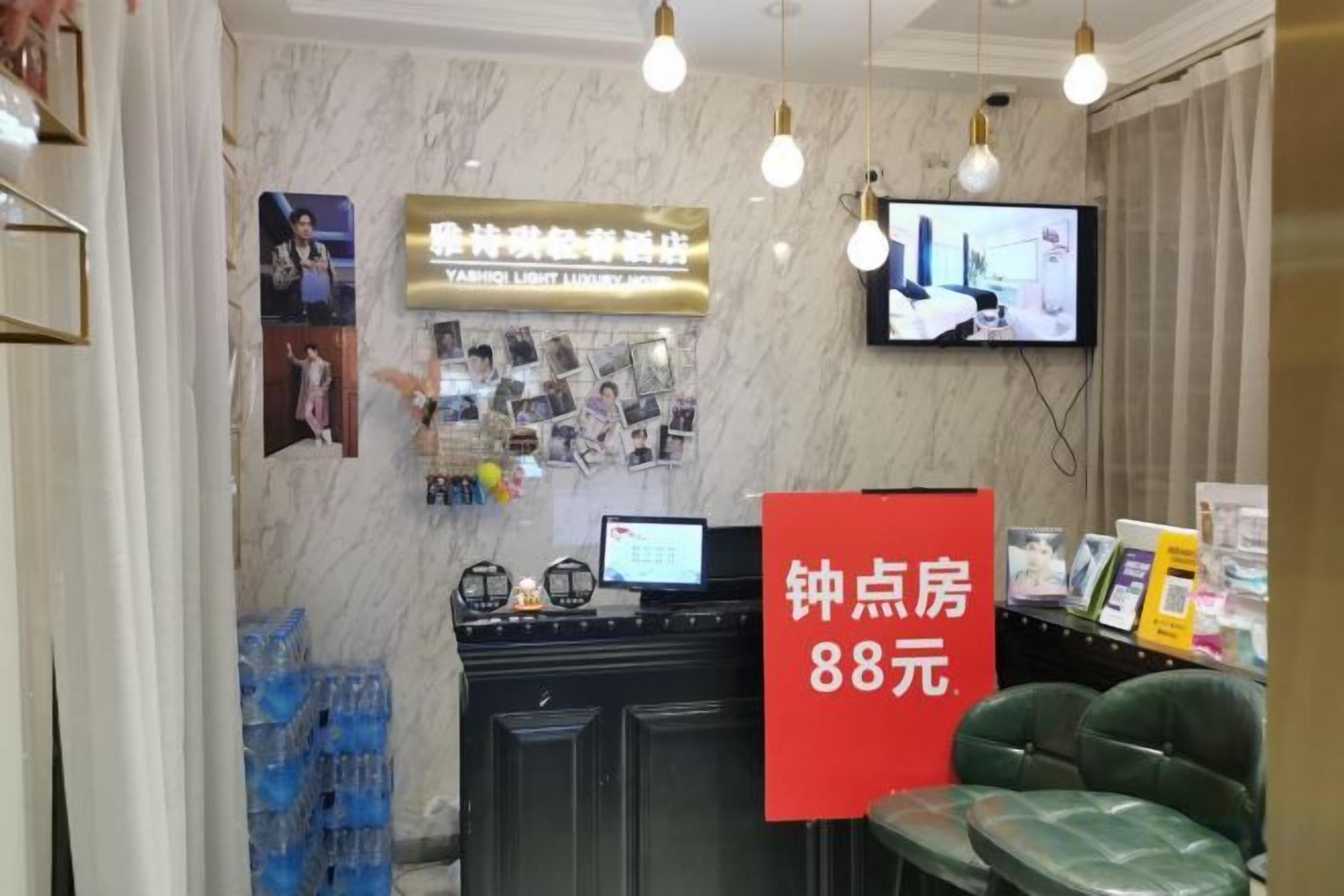 A hotel reception area with a TV, a red sign indicating room rates, and a reception desk.