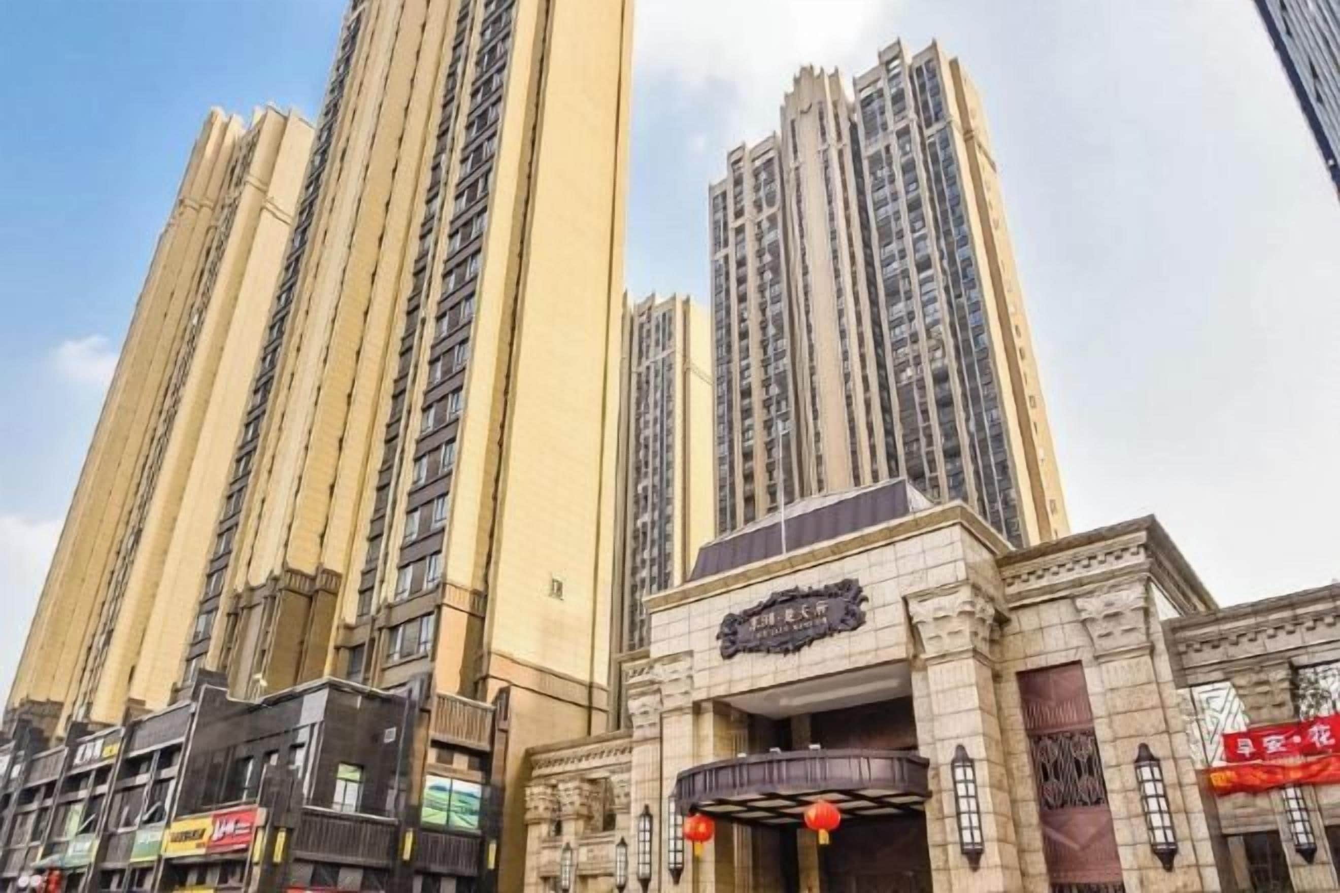 Un edificio alto con varios pisos, una entrada destacada con un letrero y un cielo despejado.