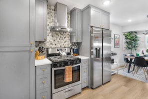 A modern kitchen with grey cabinetry, a stainless steel range, and a built-in oven.