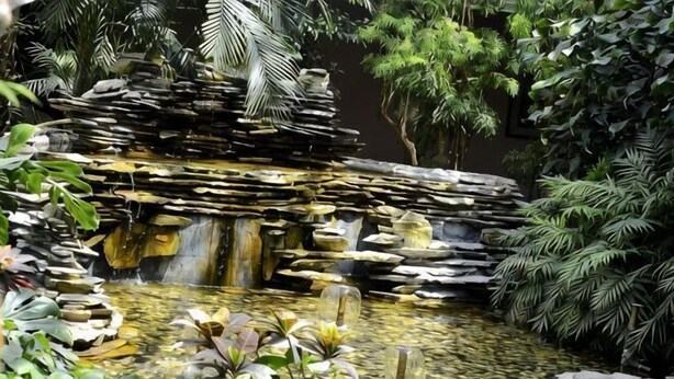 A rock waterfall in a garden with various plants. - Dongying Garden Hotel (Lanzhou University Railway Station) (Lanzhou)