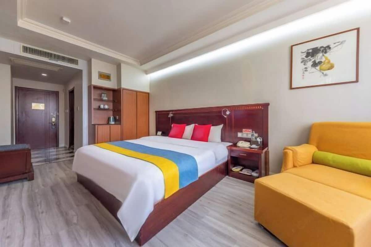 Habitación de hotel con cama, mesita de noche, una silla y un cuadro en la pared.