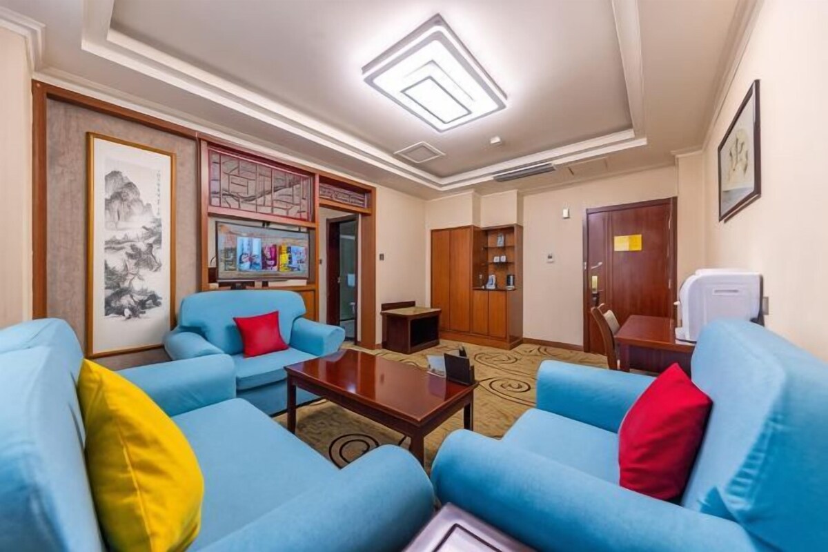 Une chambre d’hôtel dotée d’un coin salon avec des canapés bleus, une table basse et une bibliothèque.