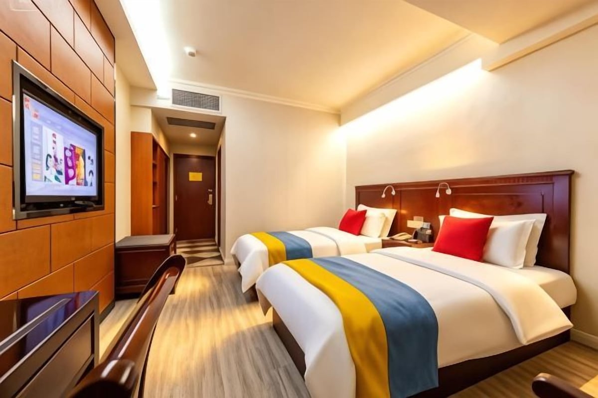 Une chambre d’hôtel avec deux lits, une télévision et un bureau.
