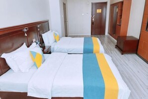 Two beds with white bedding and blue and yellow accents, a wooden headboard, and a wooden wardrobe. - Dongying Garden Hotel (Lanzhou University Railway Station) (Lanzhou)