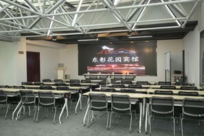 A conference room with a projection screen displaying text, rows of tables, and chairs. - Dongying Garden Hotel (Lanzhou University Railway Station) (Lanzhou)