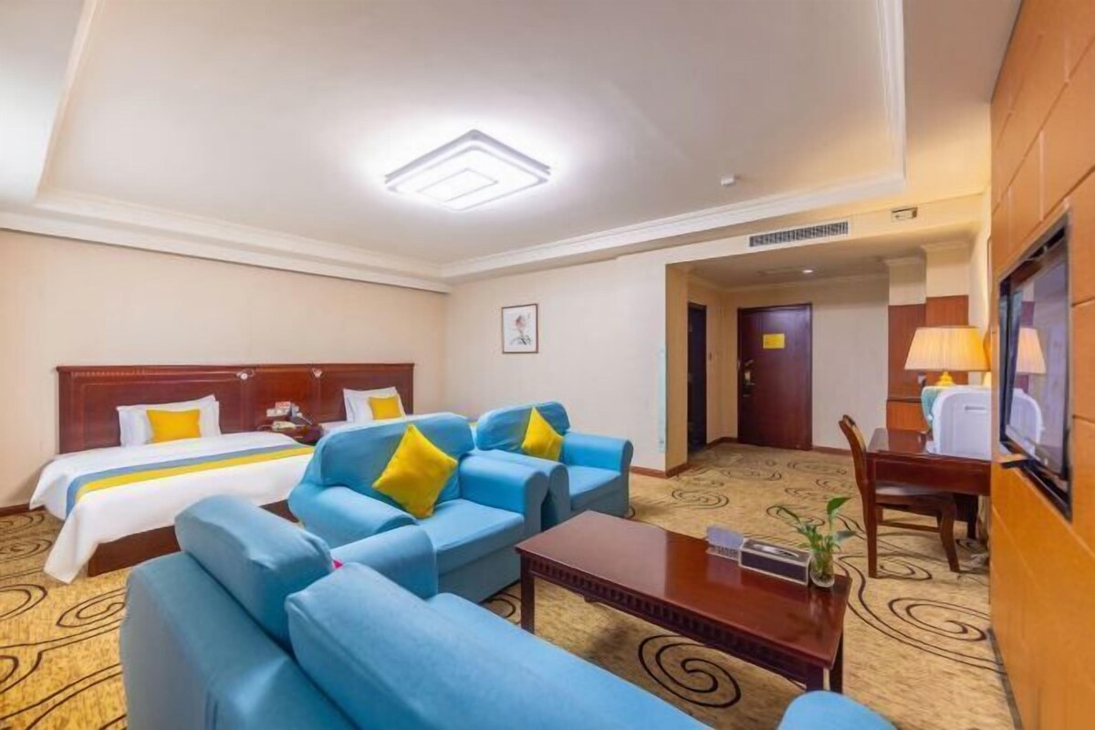 A hotel room with a bed, blue sofa, and a small table.