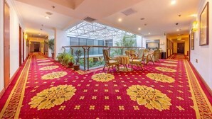 A hotel corridor with a red carpet, a dining area with chairs and a table, and a large window. - Dongying Garden Hotel (Lanzhou University Railway Station) (Lanzhou)