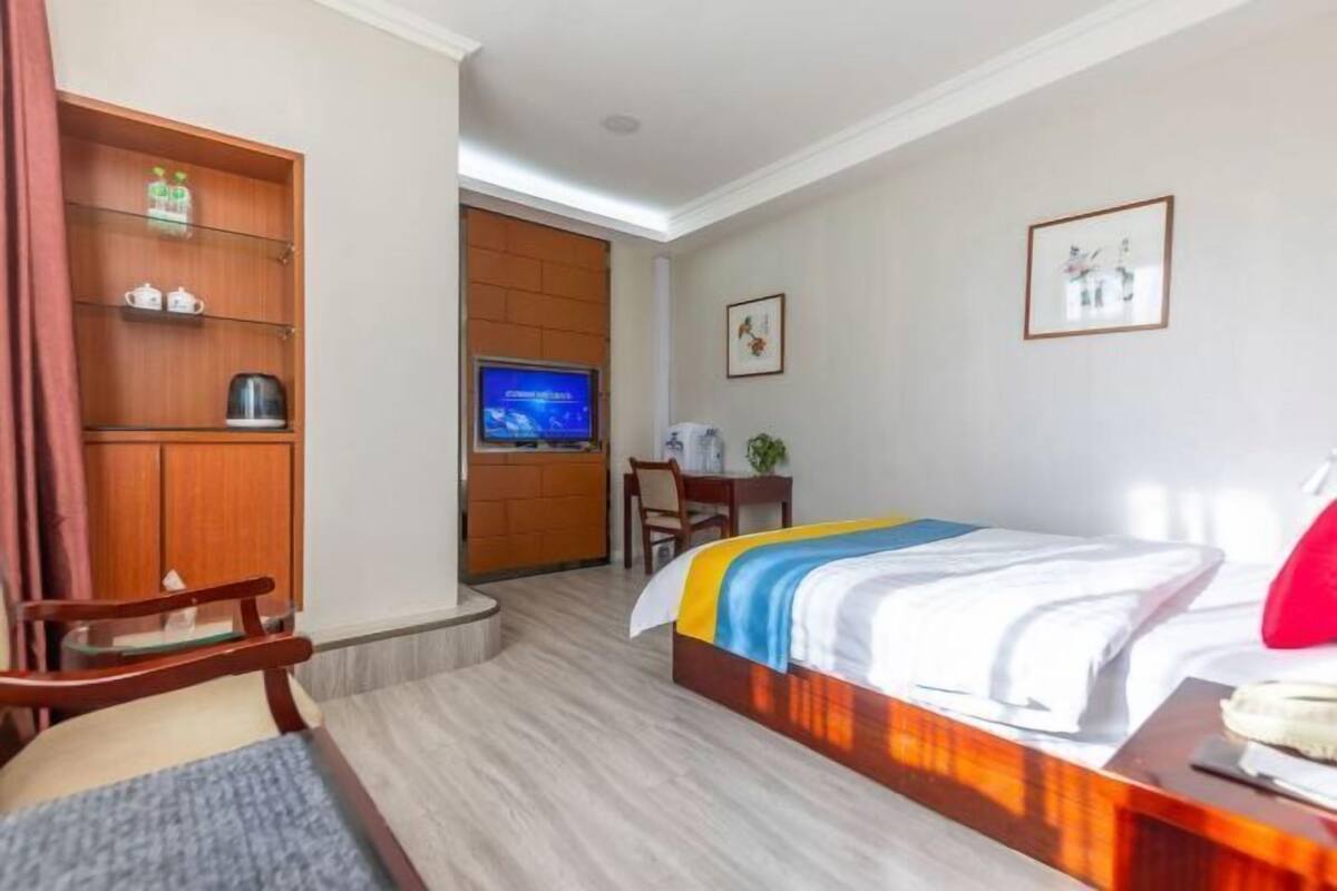 Habitación de hotel con cama, escritorio, televisor, silla y armario.