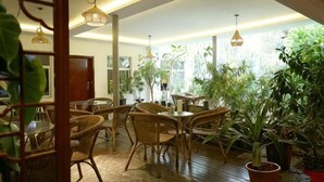 Una habitación con muebles de mimbre, ventanas amplias y luces colgantes.
