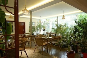 Una habitación con muebles de mimbre, ventanas amplias y luces colgantes.