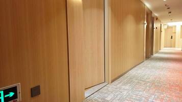A hotel corridor with wooden walls, a patterned carpet, and an emergency exit sign.