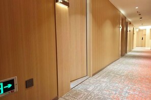 Un couloir d’hôtel avec des murs en bois, une moquette à motifs et un panneau indiquant la sortie de secours.