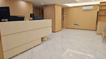 A reception area with a reception desk, a flat-screen TV, and a wooden wall.