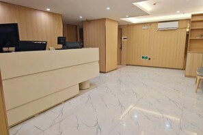 Un espace d’accueil comprenant un comptoir de réception, un téléviseur à écran plat et un mur en bois.