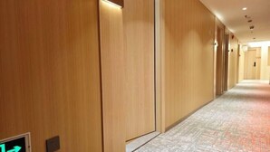 A hotel corridor with wooden walls, a patterned carpet, and an emergency exit sign. - fengyuhotel (Shanghai)