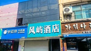 A hotel facade with a blue sign, a closed shutter, and an air conditioning unit. - fengyuhotel (Shanghai)