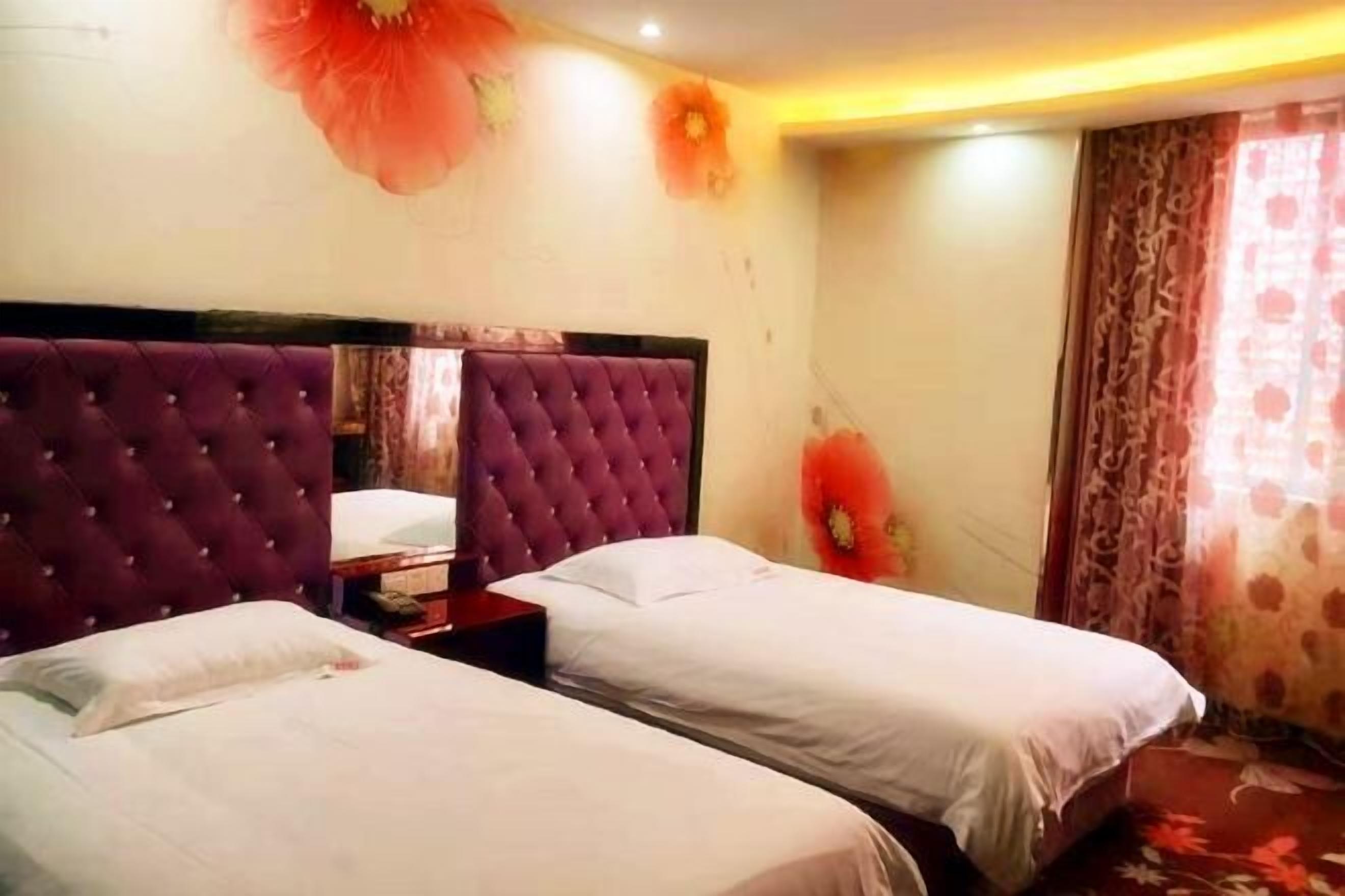 Ein Hotelzimmer mit zwei Betten, einem großen Spiegel und floralen Wanddekorationen.