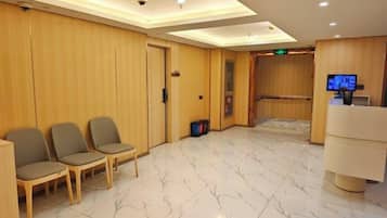 A hotel lobby with a reception desk, seating area, and a wooden wall.