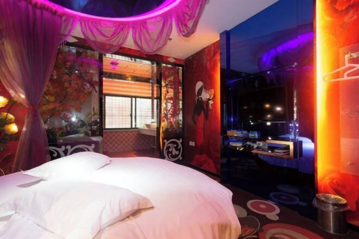 Een kamer met een bed, een raam met gordijnen, een ventilator en een decoratief object aan de muur.