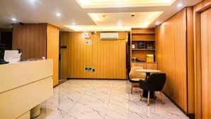 A hotel reception area with a reception desk, a seating area with chairs, a wall-mounted air conditioning unit, and a ceiling with recessed lighting. - fengyuhotel (Shanghai)